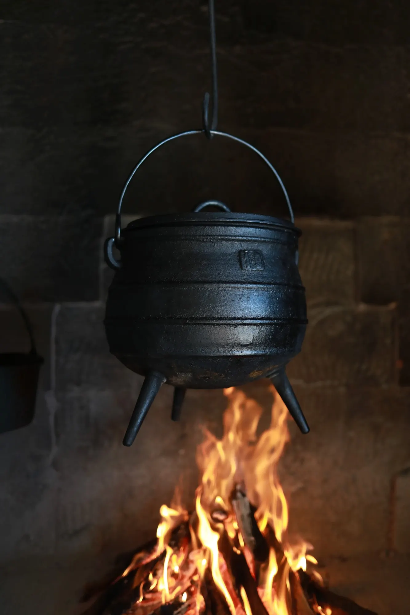 Marmite en fonte à trois pieds suspendue au-dessus d'un feu de bois